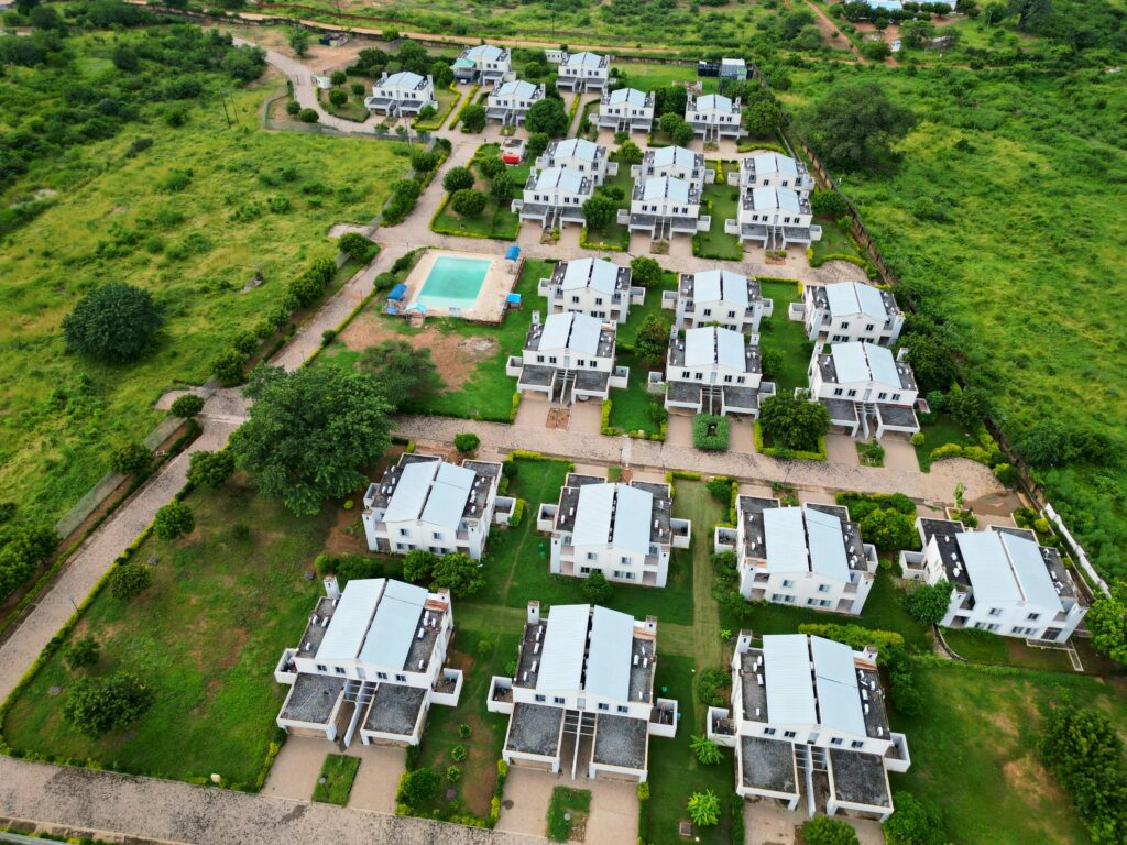 Aerial shot of a residential complex with swimming pool, surrounded by lush greenery.